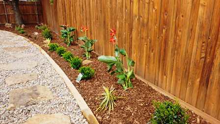 Landscapers clean flower beds and add mulch